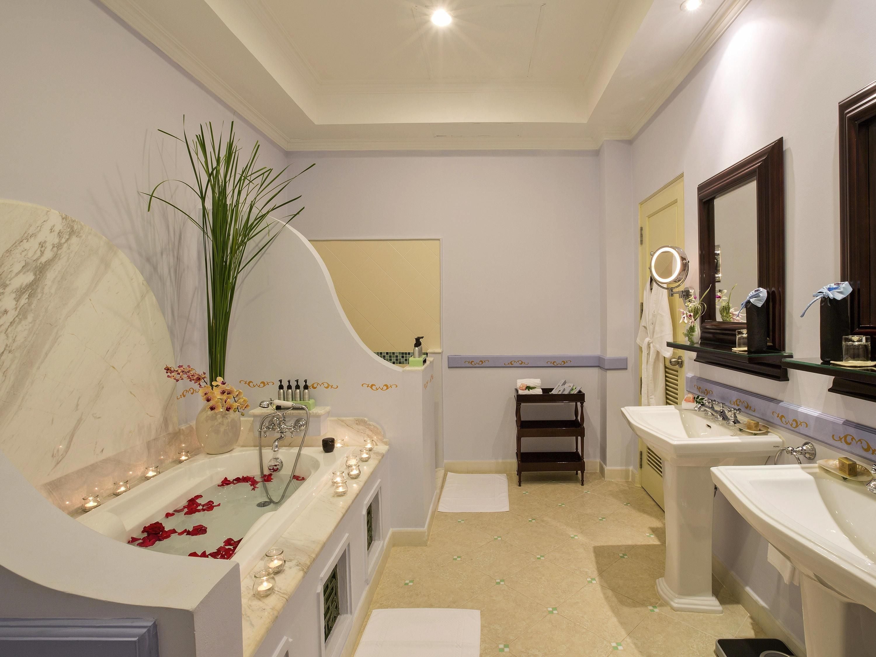 Un baño con bañera de mármol, dos lavamanos, tocador y espejo.