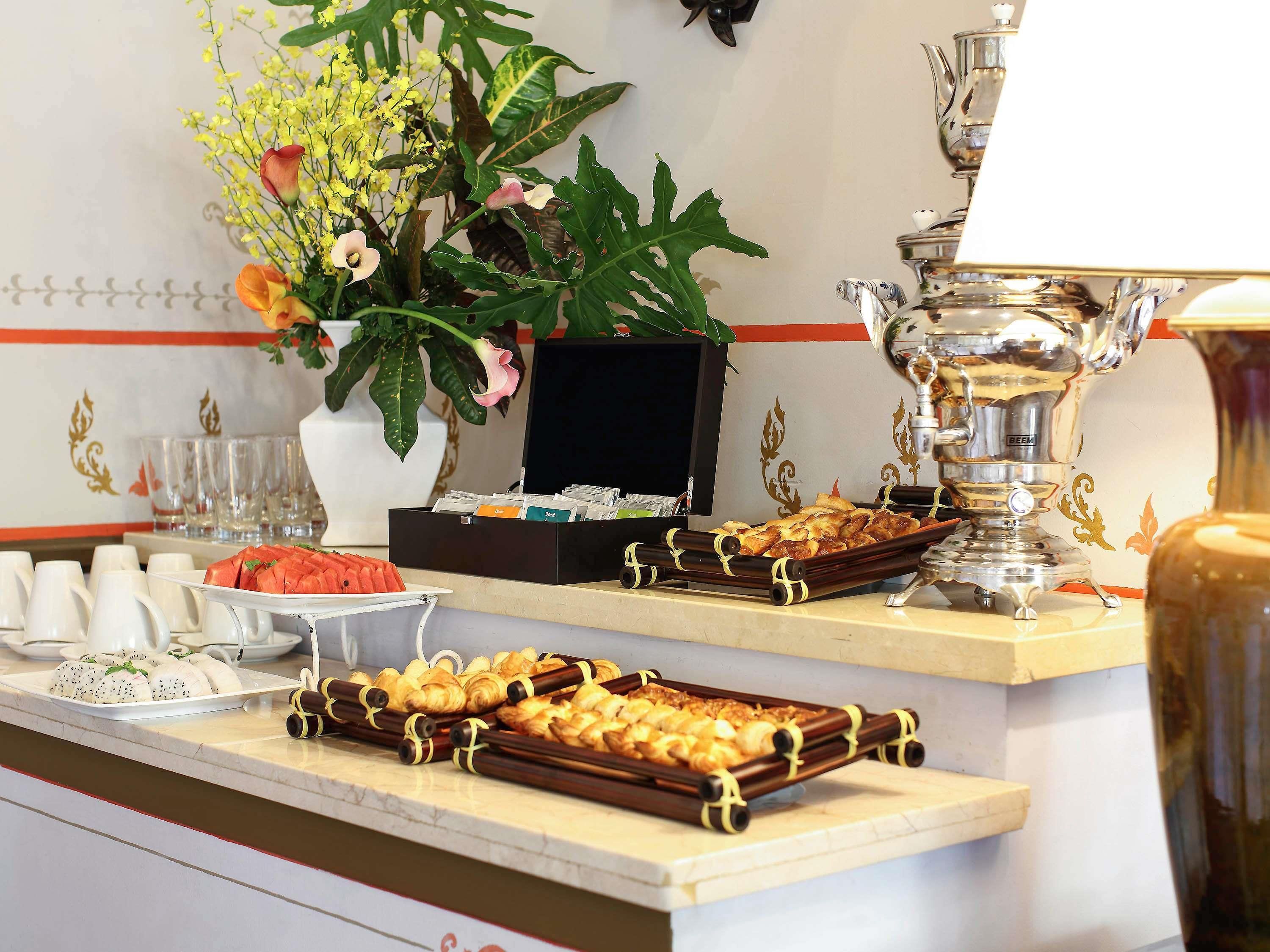 A buffet setup with various food items, a coffee machine, and a decorative plant.