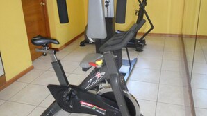 A gym with stationary bikes, a weight machine, and a window with a view of trees.