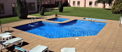 Una piscina al aire libre, sillones reclinables de piscina