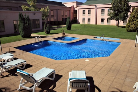Una piscina al aire libre, sillones reclinables de piscina