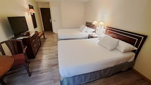 A hotel room with two beds, a desk with a chair, a television, and a door.