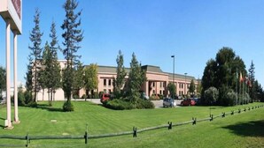 A building with a large lawn in front, surrounded by trees and a clear sky.
