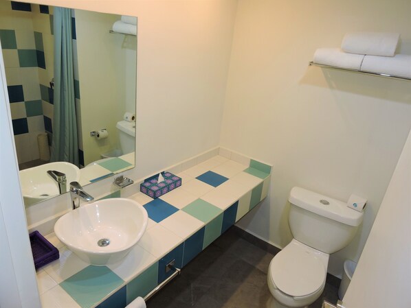 A bathroom with a white sink, a mirror, a toilet, and a towel rack.
