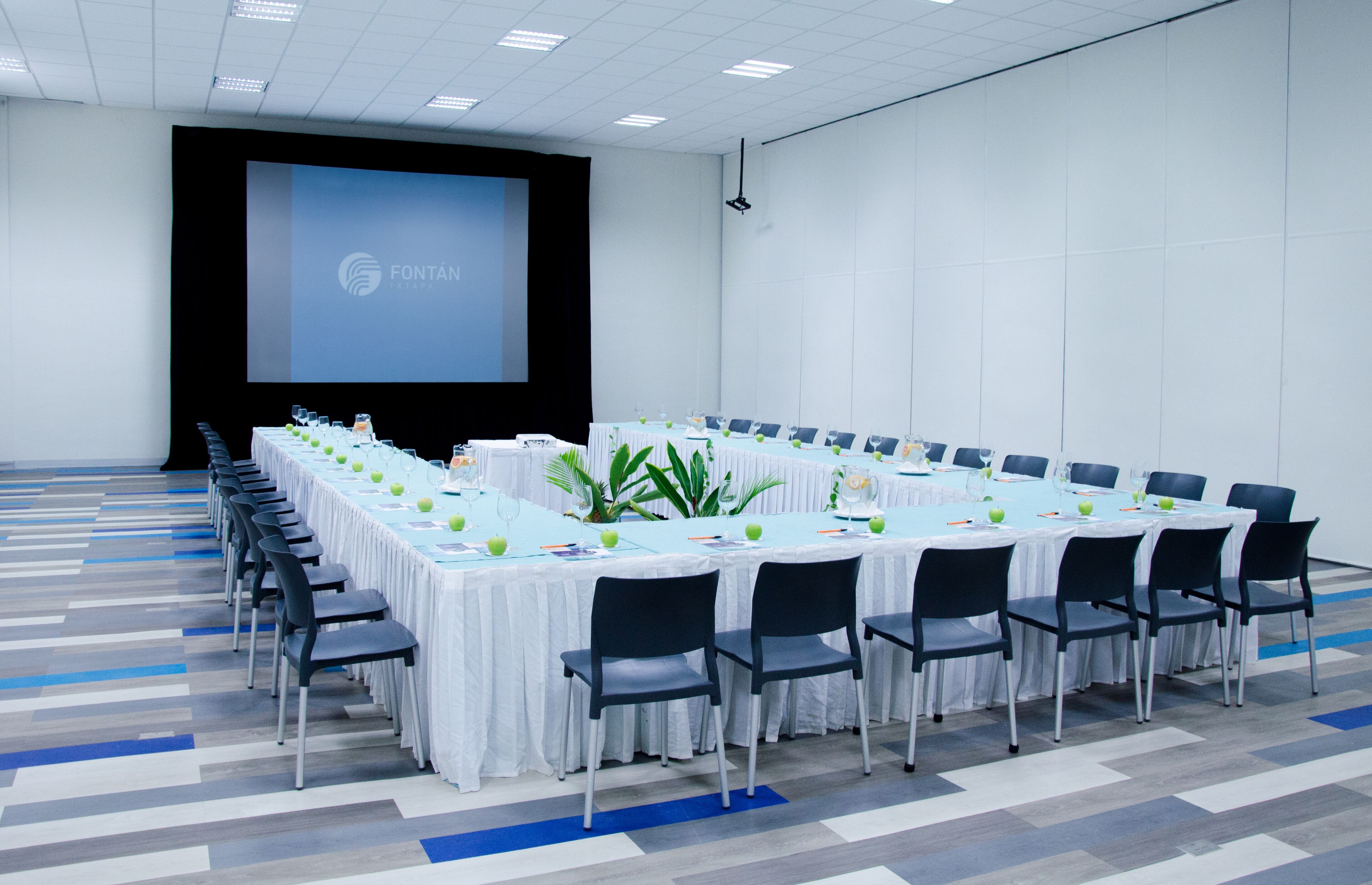 A conference room with a long table, chairs, a projector screen, and a whiteboard.