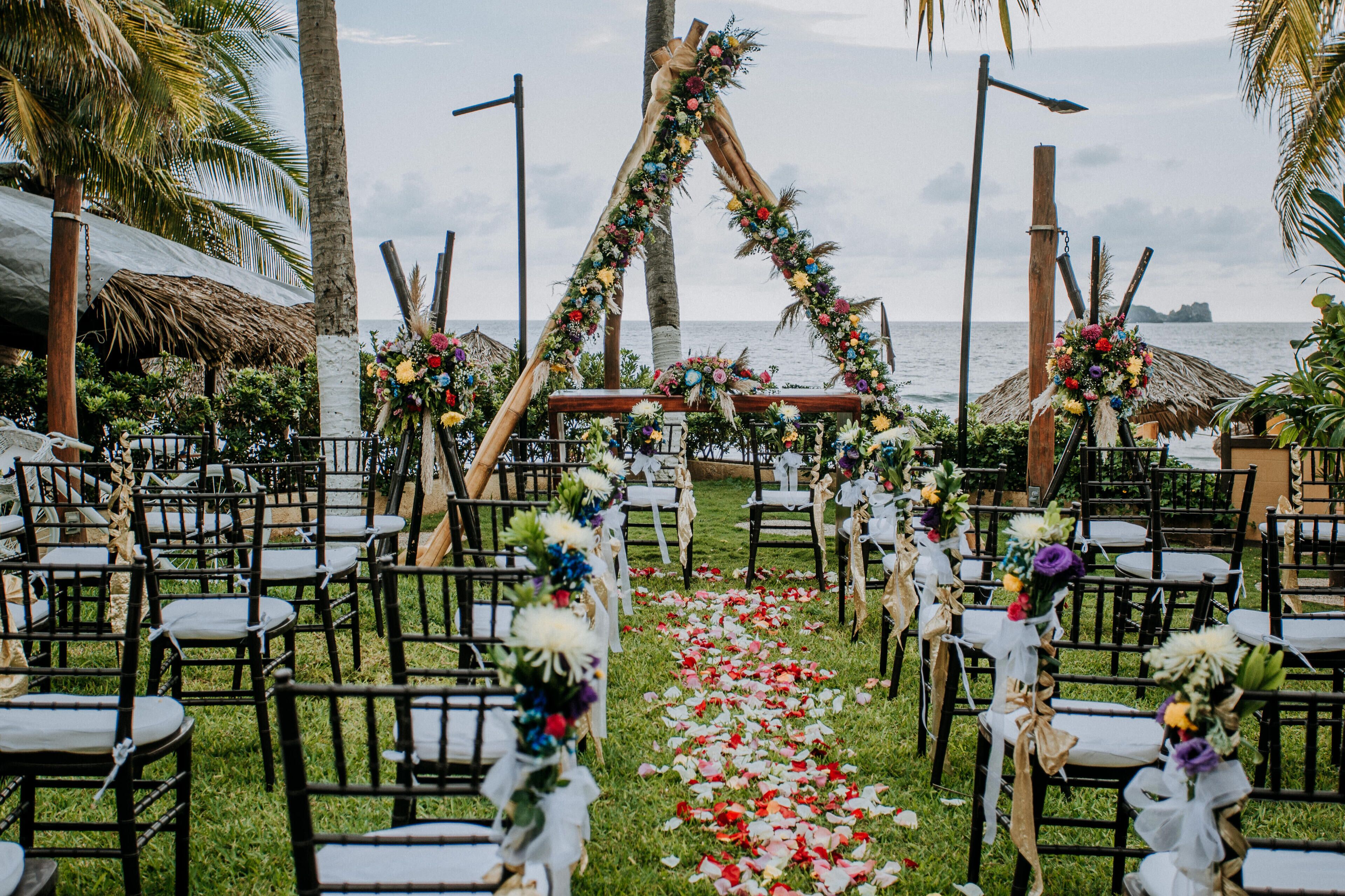 An outdoor wedding venue with rows of chairs and a floral archway.