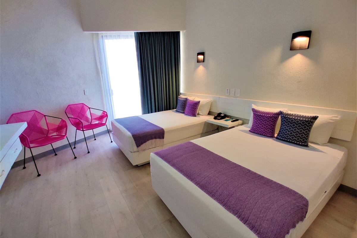 Hotellihuone, jossa on kaksi sänkyä, työpöytä ja tuoli.