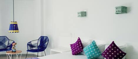 Ein modernes Hotelzimmer mit einem Bett, zwei Stühlen, einem kleinen Tisch und einer Pendelleuchte.
