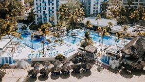 A resort with multiple swimming pools, palm trees, and beachfront seating areas. - Fontan Ixtapa Beach Resort - All Inclusive (Ixtapa)