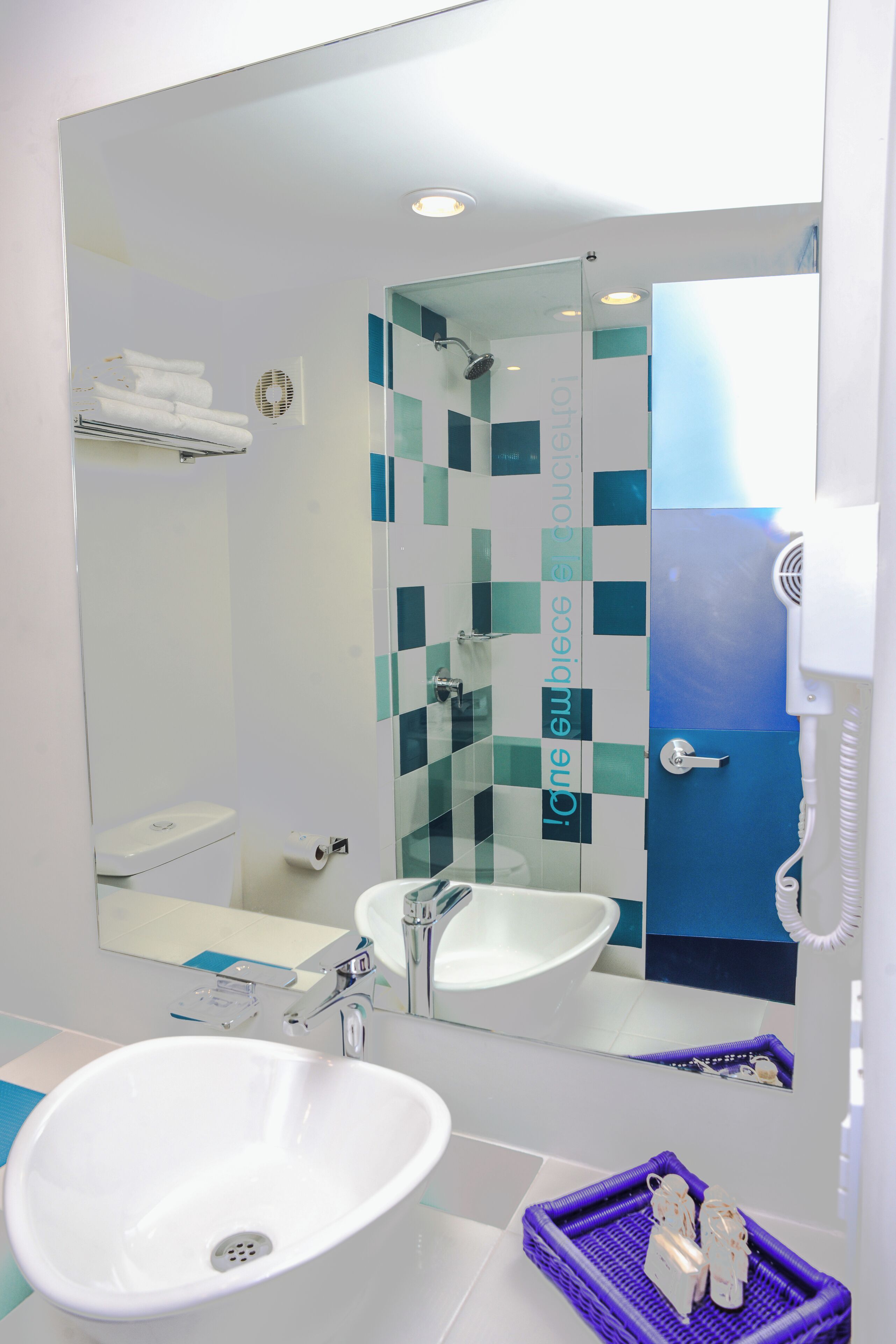 A modern bathroom with a white sink, a glass shower enclosure, and a large mirror.