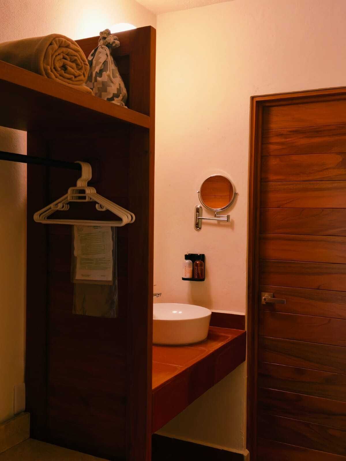 A bathroom with a wooden door, a towel rack, a mirror, and a sink.