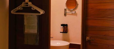 A bathroom with a wooden door, a towel rack, a mirror, and a sink.