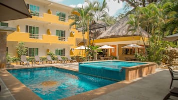 Alberca al aire libre, sombrillas en la alberca y camastros