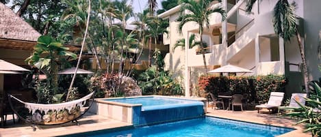 Una piscina al aire libre, sombrillas, sillones reclinables de piscina