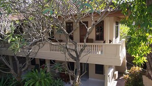 A two-story building with a balcony, surrounded by lush greenery. - Hotel Flamboyan (Kuta)