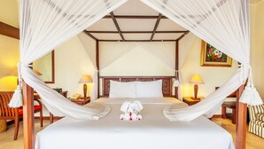 A hotel room with a bed under a canopy, a bedside table with a lamp, a chair, and a painting on the wall. - Puri Bunga Resort & Spa (Ubud)
