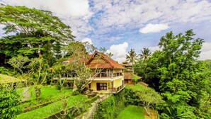 A two-story house with a balcony, surrounded by lush greenery and a clear sky. - Puri Bunga Resort & Spa (Ubud)