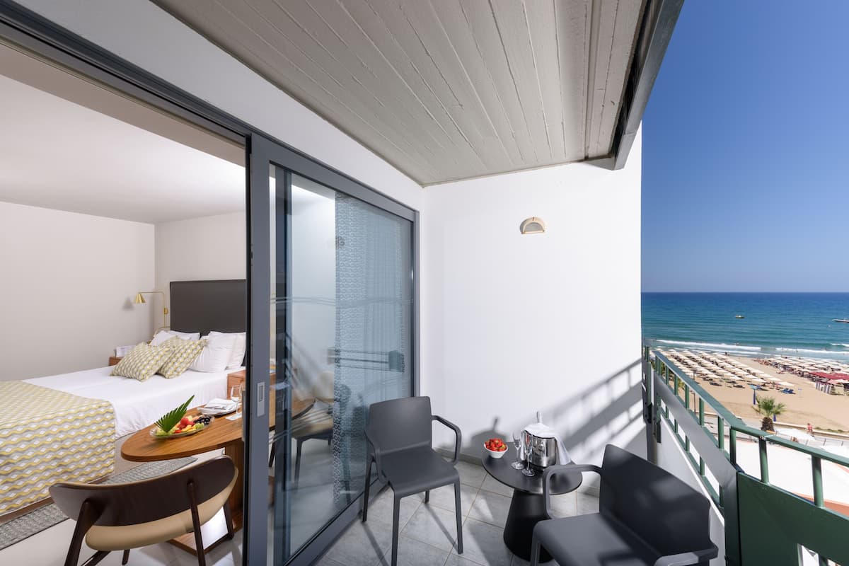 Uma varanda com cama, mesa de jantar e vista para a praia.