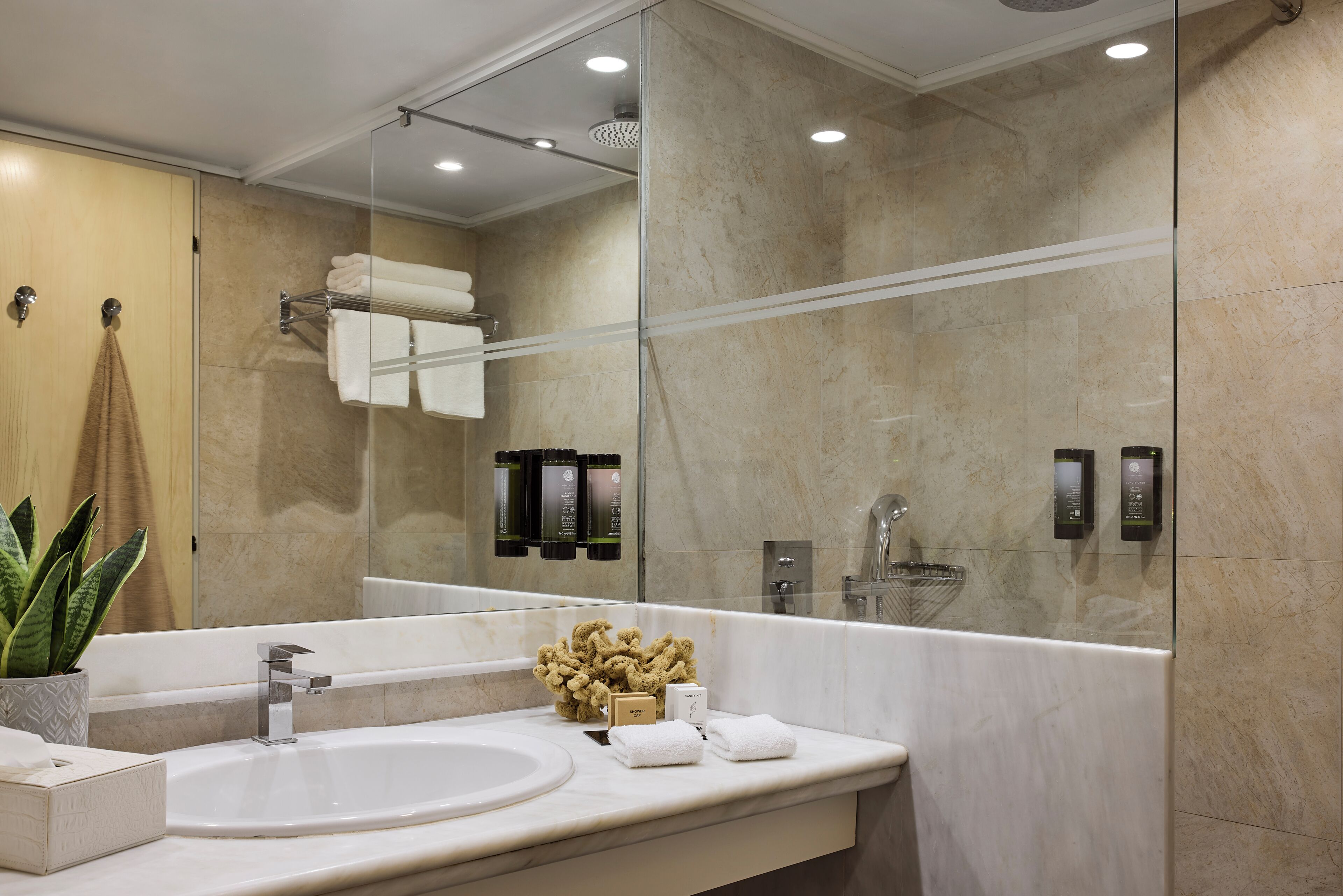 Een moderne badkamer met een grote spiegel, een wastafel, een douche en een handdoekrek.