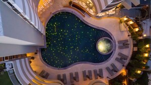 An aerial view of a hotel with a central pool surrounded by lounge areas and outdoor seating. - Aquila Porto Rethymno (Rethymno)