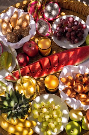 A variety of fruits and pastries arranged on a woven basket.