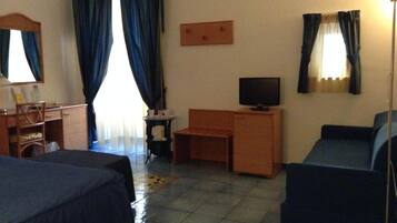 Una habitación de hotel con dos camas, un escritorio, un televisor y un sofá.