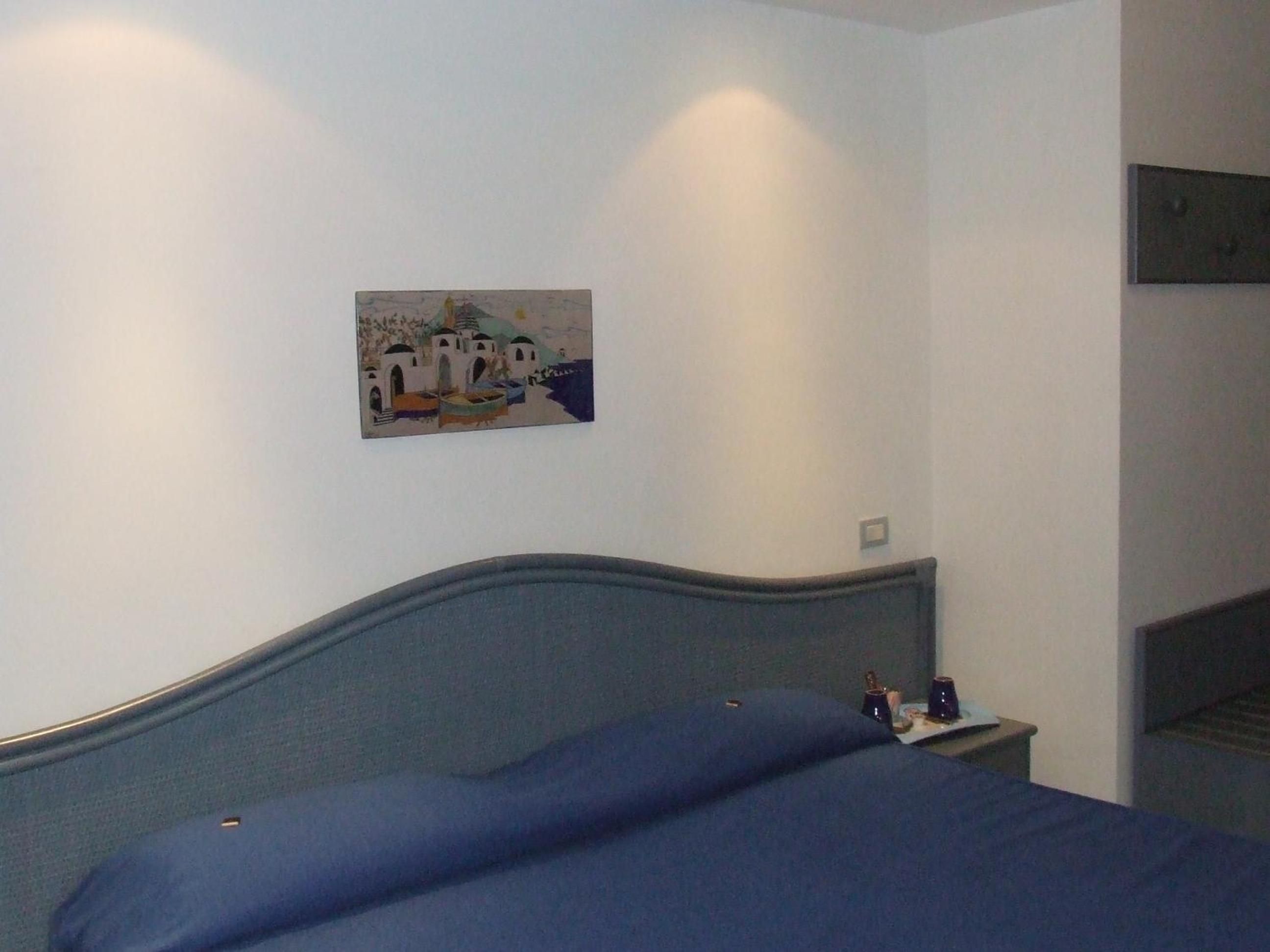 Quarto com cama, mesa de cabeceira e pintura na parede.