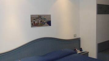 Quarto com cama, mesa de cabeceira e pintura na parede.