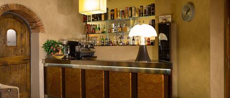 A bar area with a wooden counter, shelves with bottles, a clock, and a sign that reads "toilette".
