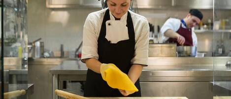 A chef preparing food in a professional kitchen with stainless steel appliances and a clean, organized workspace.