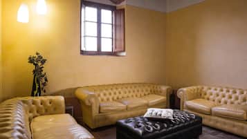 Un salon avec un canapé beige, un pouf noir et une plante en pot.