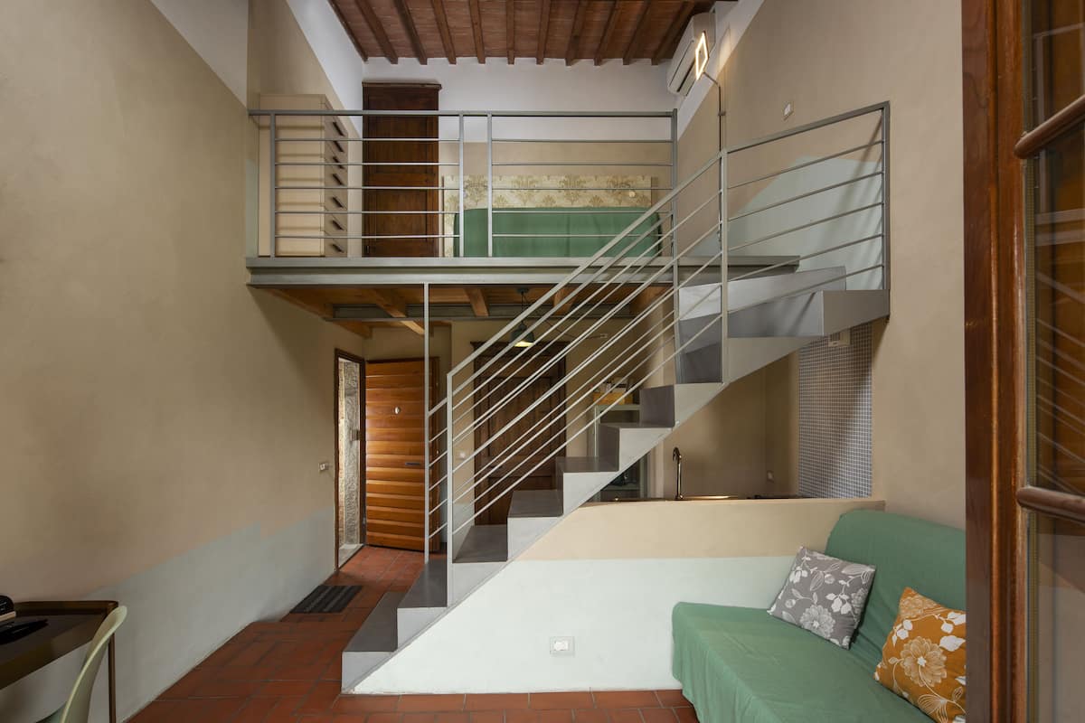 A multi-level interior with a staircase, a green sofa, and a wooden door.