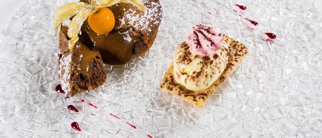 Un postre con pastel de chocolate, una bola de helado y un trozo de pastel sobre un plato de vidrio.