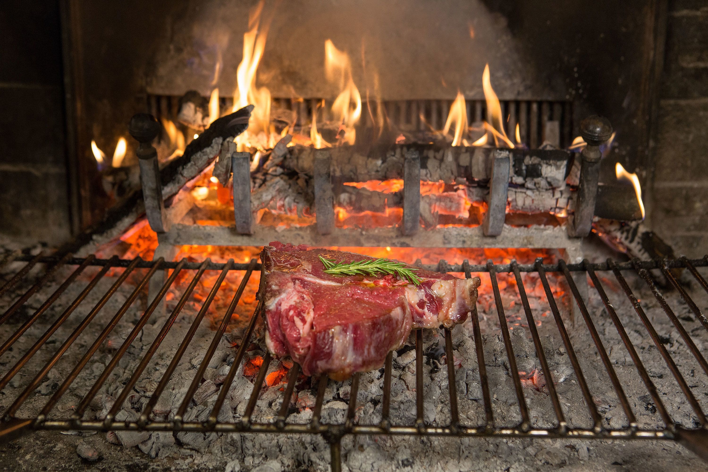 Un filete asándose sobre una parrilla metálica al fuego abierto.