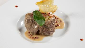 A plate with a meat dish, sauce, and a garnish.