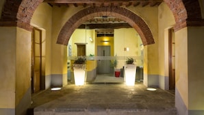 A hotel lobby with a brick archway, a reception desk, and potted plants. - Hotel Le Capanne (Arezzo)