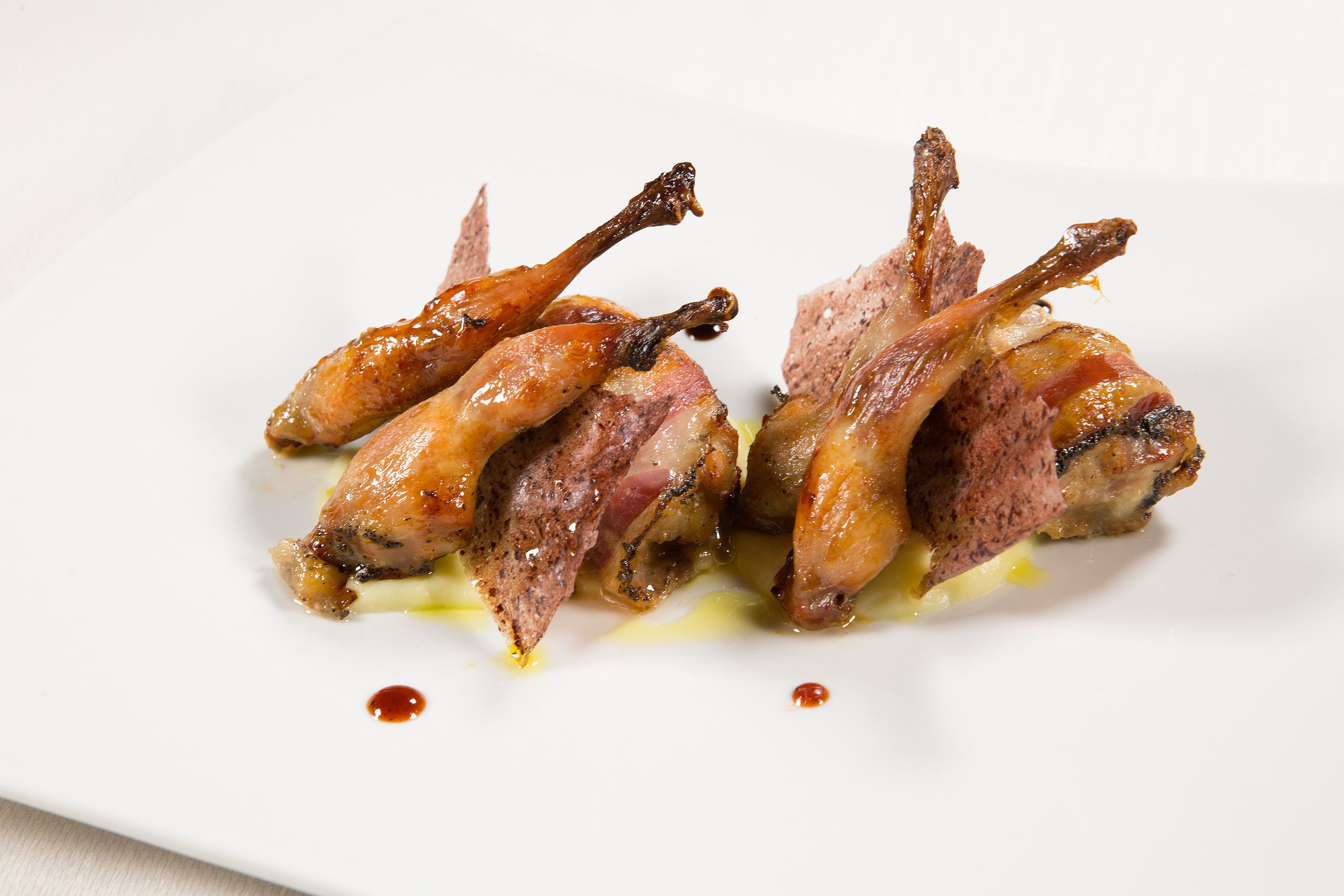 A plate of cooked duck legs with sauce.