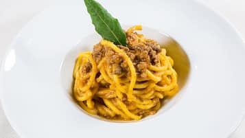 Un piatto di spaghetti con ragù e una foglia di alloro come guarnizione.