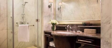 Un baño moderno con ducha de vidrio, tocador de mármol y un espejo grande.