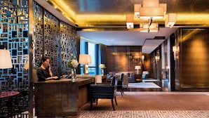 Un moderno vestíbulo de hotel con mostrador de recepción, zona de estar y paneles decorativos en la pared.