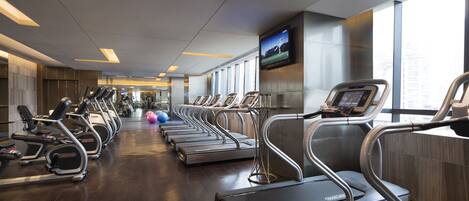 A gym with treadmills, elliptical machines, and exercise balls.
