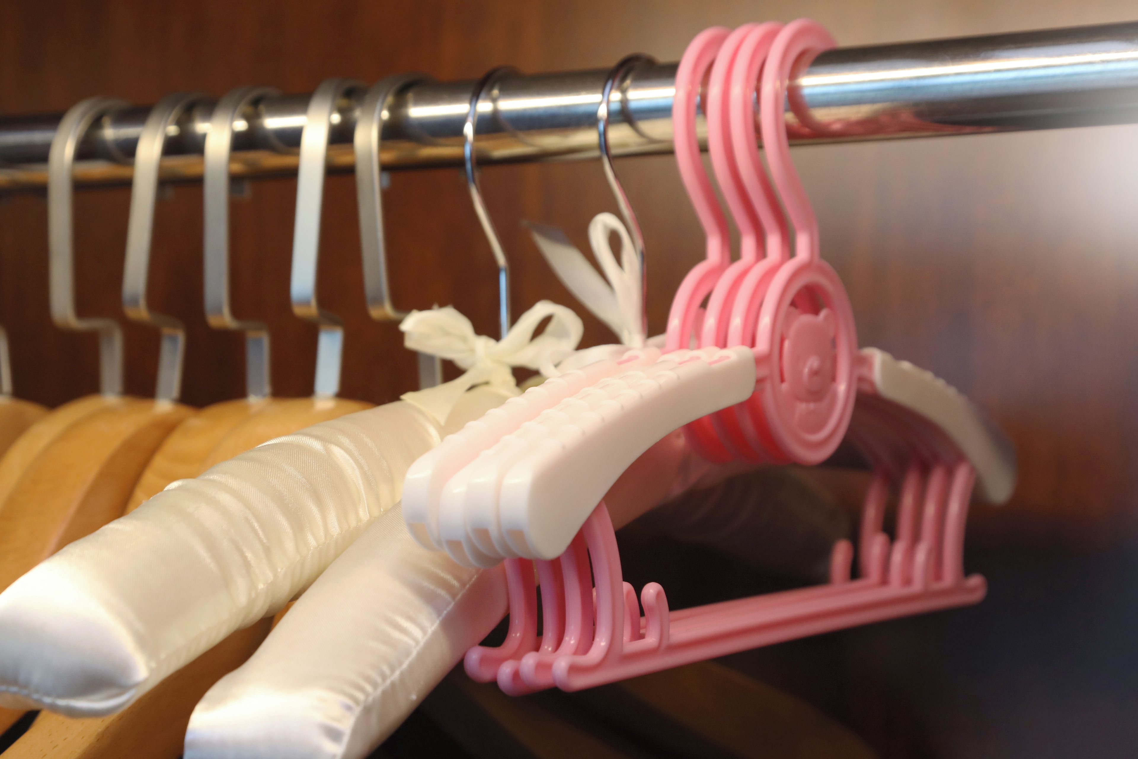 A clothing rack with white and pink hangers.
