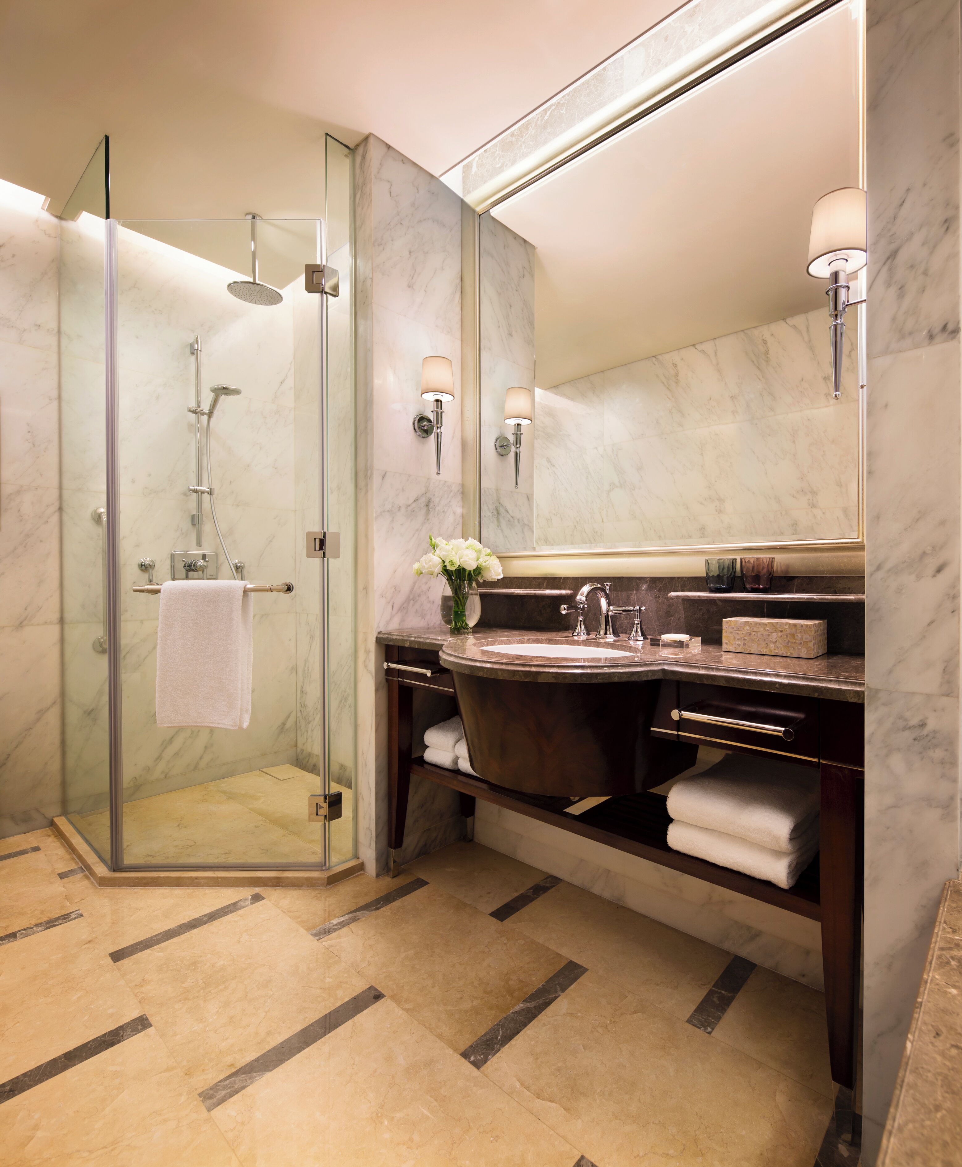 A modern bathroom with a glass-enclosed shower, a large mirror, and a vanity with a sink and towel rack.