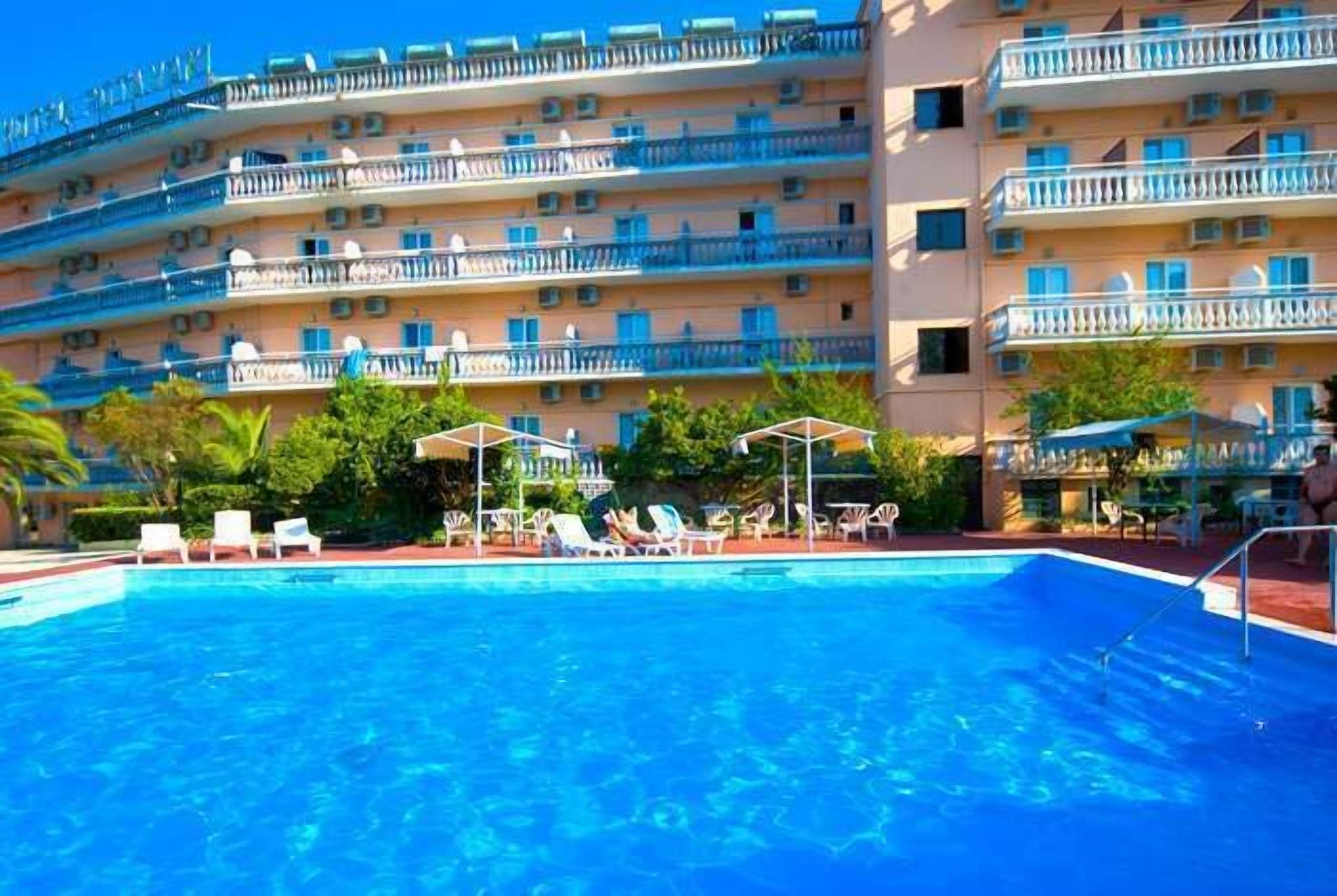 A hotel with a swimming pool, multiple balconies, and outdoor seating areas.