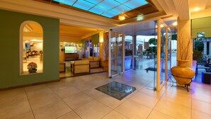 A hotel lobby with a reception desk, seating area, and a large vase. - Potamaki Beach Hotel (Corfu)