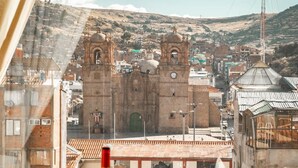 A dining table set with plates, glasses, and a bottle, overlooking a historic town with a prominent church and clock tower. - Hacienda Puno (Puno)