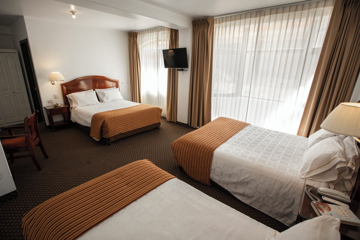 A hotel room with two beds, a TV, a desk, and a chair.