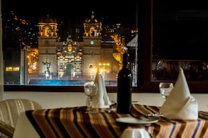 Mesa lista para cenar con vista a un edificio histórico por la noche.
