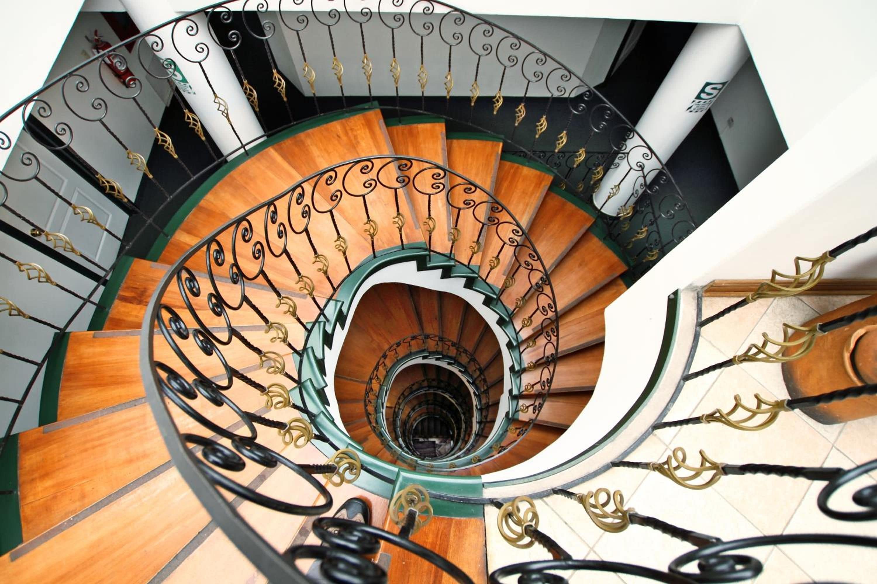 Una escalera en espiral con detalles de madera y barandillas de metal.