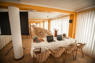 Una sala de conferencias con una mesa larga, sillas, un atril y portátiles.